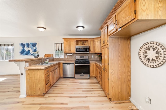 kitchen featuring stainless steel appliances, plenty of natural light, light wood-type flooring, and sink