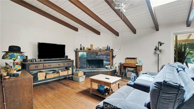 living room featuring vaulted ceiling with beams, a premium fireplace, and hardwood / wood-style floors