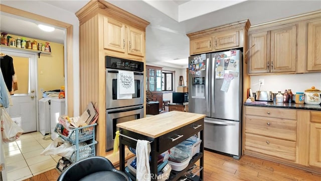 kitchen featuring light wood-type flooring, appliances with stainless steel finishes, light brown cabinets, and washing machine and dryer