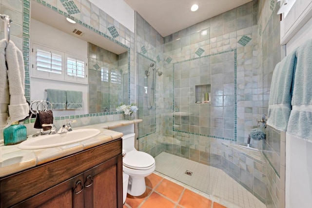 bathroom with a shower with door, vanity, toilet, and tile patterned floors