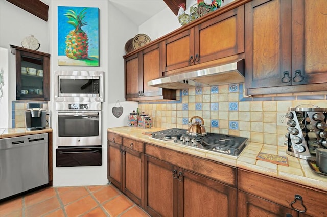 kitchen with stainless steel appliances, backsplash, and light tile patterned floors