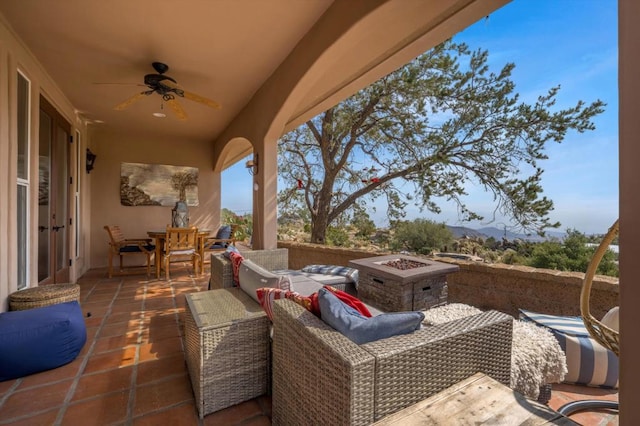 view of patio featuring ceiling fan, an outdoor living space with a fire pit, and a mountain view