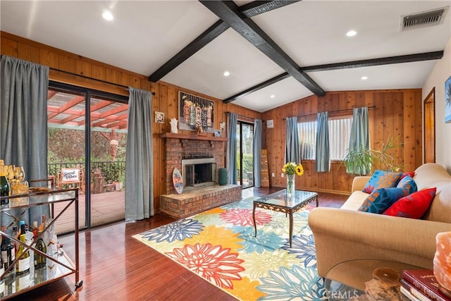 living room with a fireplace, vaulted ceiling with beams, and wood walls