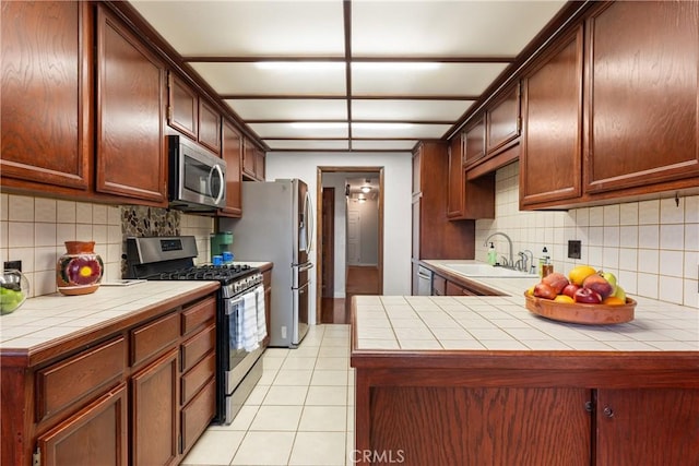 kitchen featuring tasteful backsplash, kitchen peninsula, sink, and appliances with stainless steel finishes