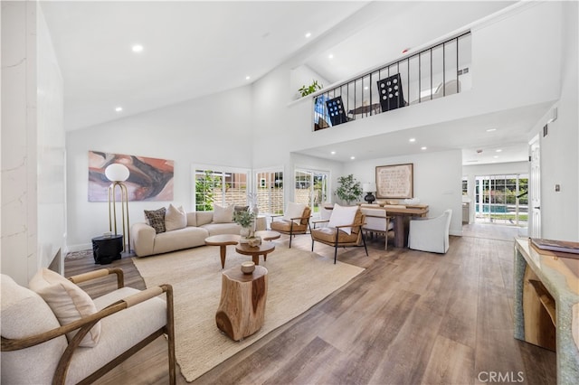 living room featuring high vaulted ceiling, light wood-type flooring, and plenty of natural light