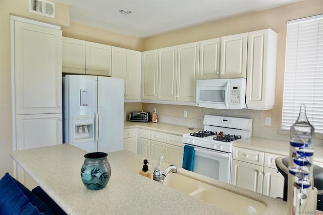 kitchen with white appliances, white cabinetry, sink, and a kitchen breakfast bar