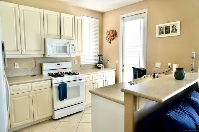 kitchen with a breakfast bar area, kitchen peninsula, white appliances, and light tile patterned floors