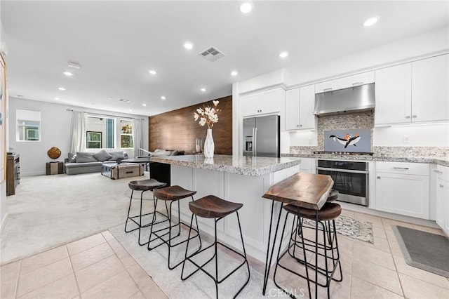 kitchen featuring light stone countertops, ventilation hood, stainless steel appliances, light colored carpet, and white cabinetry