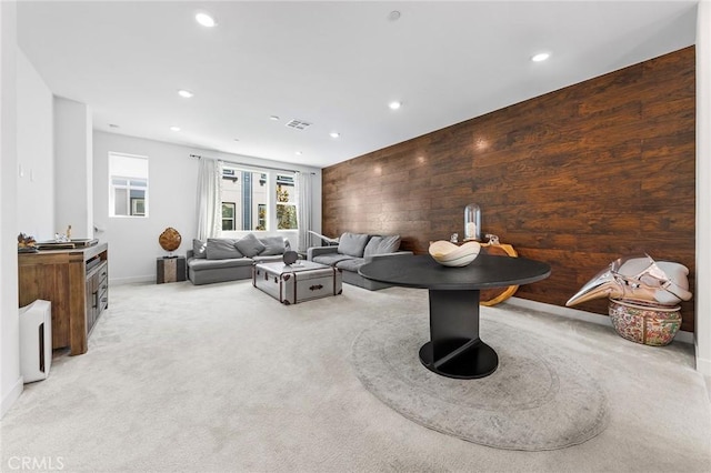 carpeted living room featuring wooden walls