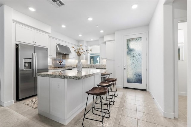 kitchen featuring white cabinets, stainless steel appliances, extractor fan, and a kitchen island