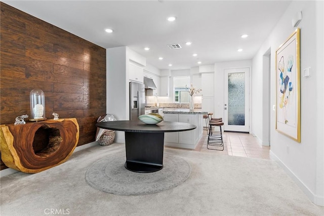 kitchen with a kitchen bar, light carpet, white cabinets, and a kitchen island