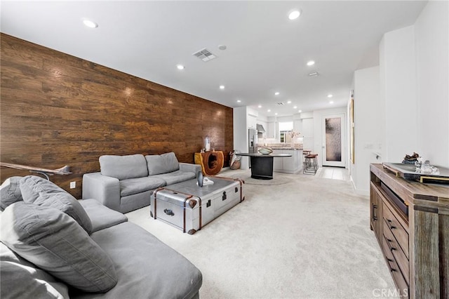 living room featuring wood walls and light carpet