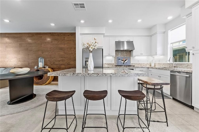 kitchen featuring stainless steel appliances, a kitchen island, and light stone counters