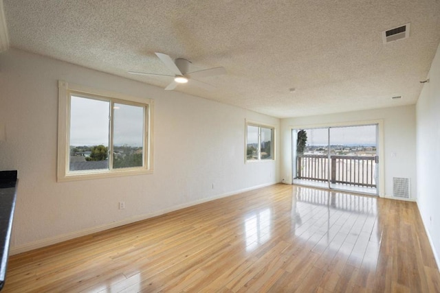 unfurnished living room with light hardwood / wood-style floors, a textured ceiling, plenty of natural light, and ceiling fan