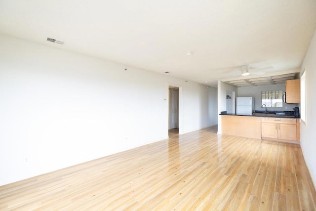 unfurnished living room featuring light hardwood / wood-style floors, sink, and ceiling fan