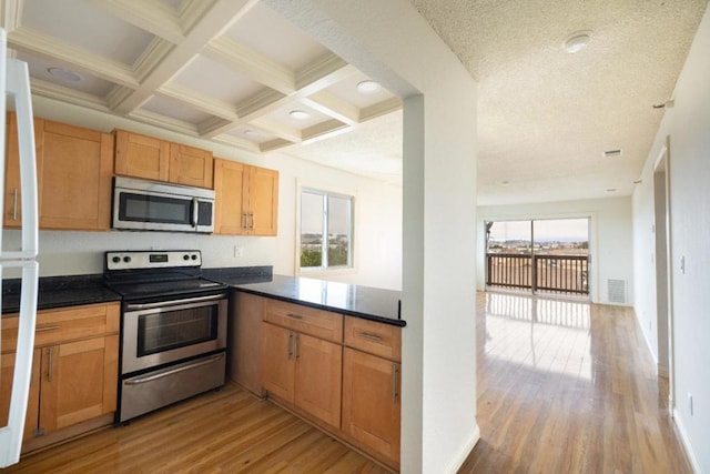 kitchen with light hardwood / wood-style floors, beam ceiling, a healthy amount of sunlight, and stainless steel appliances