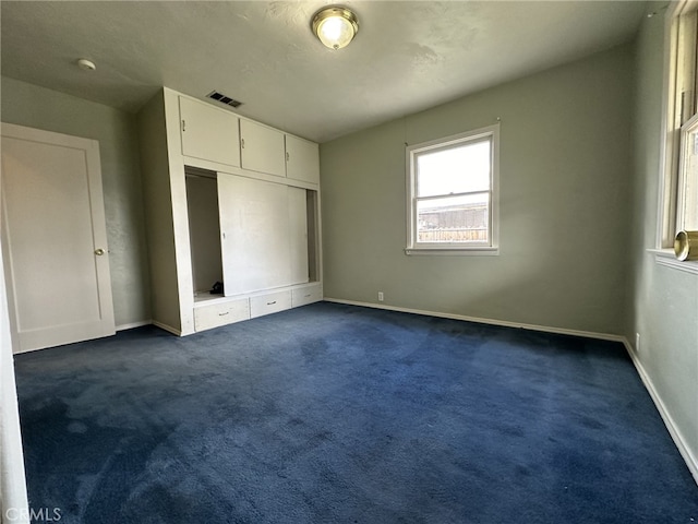 unfurnished bedroom with dark colored carpet and a closet