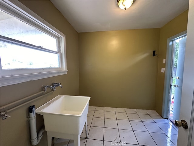 laundry area with light tile patterned floors, a healthy amount of sunlight, and sink