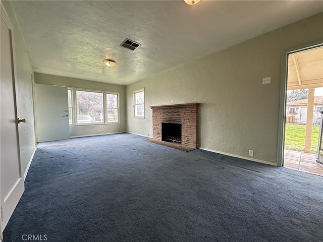 unfurnished living room with a fireplace, a textured ceiling, and dark carpet