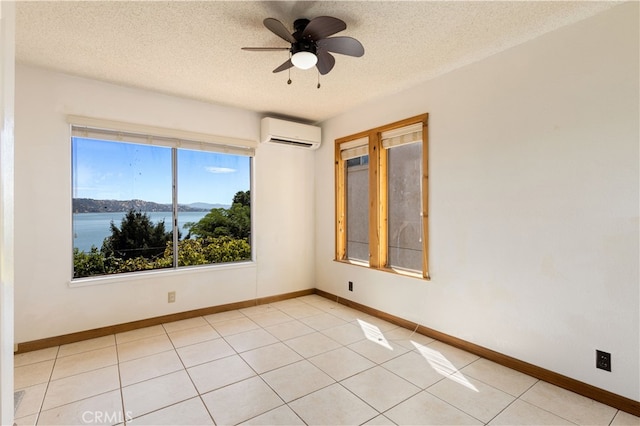 tiled spare room with a textured ceiling, a water view, ceiling fan, and a wall unit AC