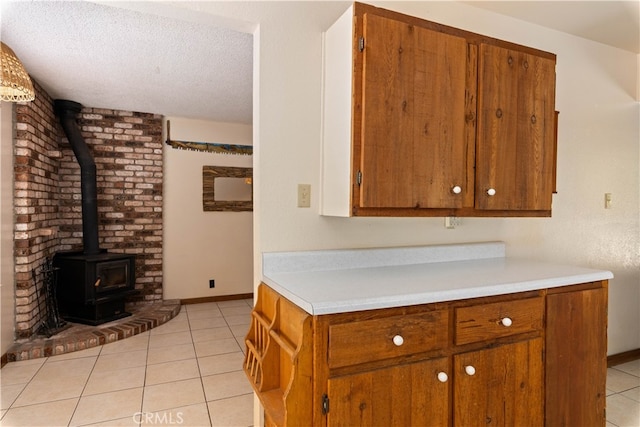 kitchen featuring brown cabinets, light countertops, a wood stove, and light tile patterned flooring