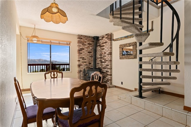 dining space featuring light tile patterned floors, stairway, a wood stove, a textured ceiling, and baseboards