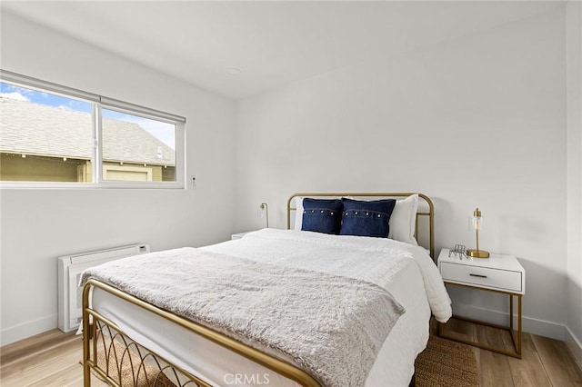 bedroom featuring radiator and light hardwood / wood-style flooring