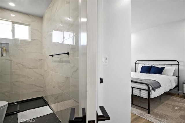 bathroom with hardwood / wood-style floors, a shower with shower door, and toilet