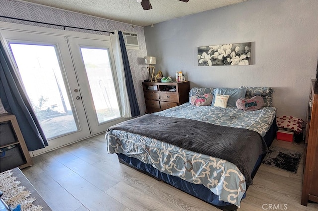bedroom featuring wood finished floors, a textured ceiling, access to outside, and french doors