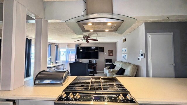 kitchen with open floor plan, stainless steel gas range oven, light countertops, and ceiling fan