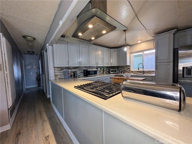 kitchen with a textured ceiling, gray cabinets, dark wood-style flooring, and stainless steel appliances
