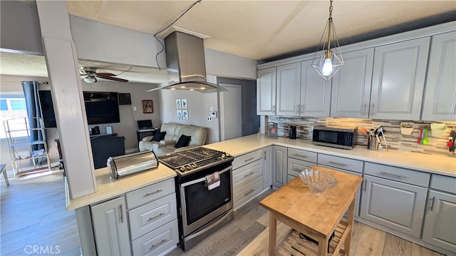 kitchen featuring ceiling fan, gray cabinets, appliances with stainless steel finishes, light wood-style flooring, and island range hood