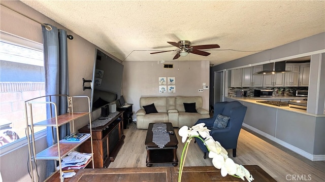 living room featuring light wood-style flooring, visible vents, a textured ceiling, and ceiling fan