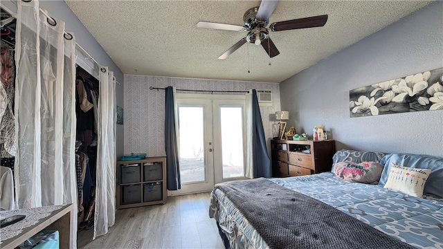 bedroom featuring light wood-style flooring, french doors, a textured ceiling, access to outside, and ceiling fan