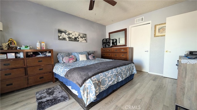 bedroom featuring wood finished floors, visible vents, a textured ceiling, and a ceiling fan