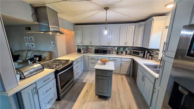 kitchen with a sink, gray cabinets, backsplash, wall chimney exhaust hood, and appliances with stainless steel finishes