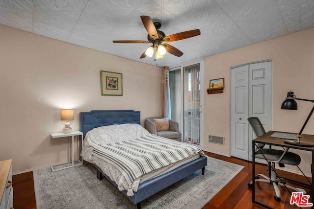 bedroom with dark hardwood / wood-style flooring, ceiling fan, and a closet