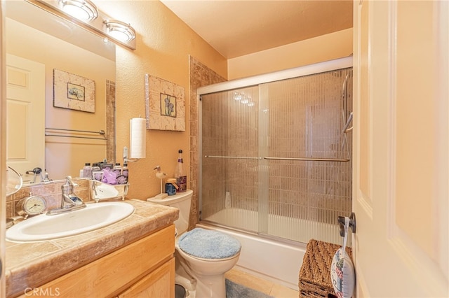 full bathroom featuring tile patterned flooring, vanity, combined bath / shower with glass door, and toilet