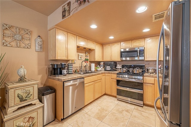 kitchen featuring appliances with stainless steel finishes, light brown cabinets, light tile patterned floors, and sink