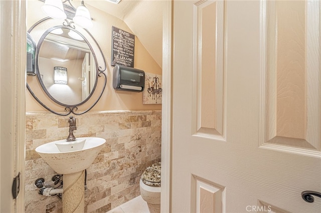 bathroom featuring toilet, tile walls, and sink