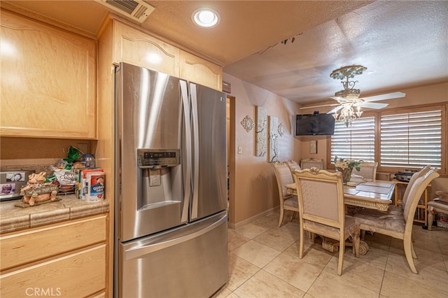 tiled dining space with ceiling fan and a textured ceiling