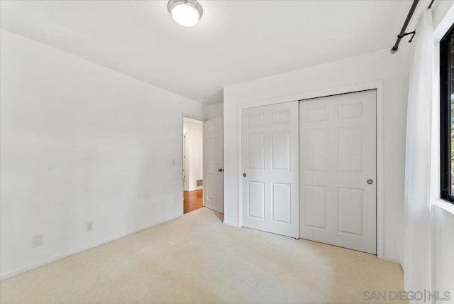 unfurnished bedroom featuring light colored carpet and a closet