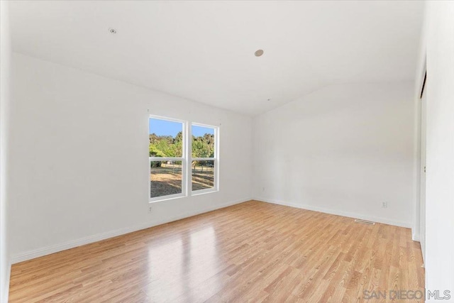 unfurnished room featuring light wood-type flooring and vaulted ceiling