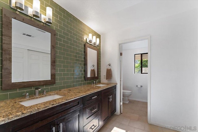 bathroom featuring vanity, tile patterned floors, tile walls, toilet, and decorative backsplash