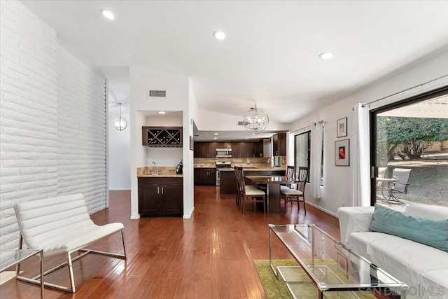 living room with an inviting chandelier, lofted ceiling, dark hardwood / wood-style floors, and sink