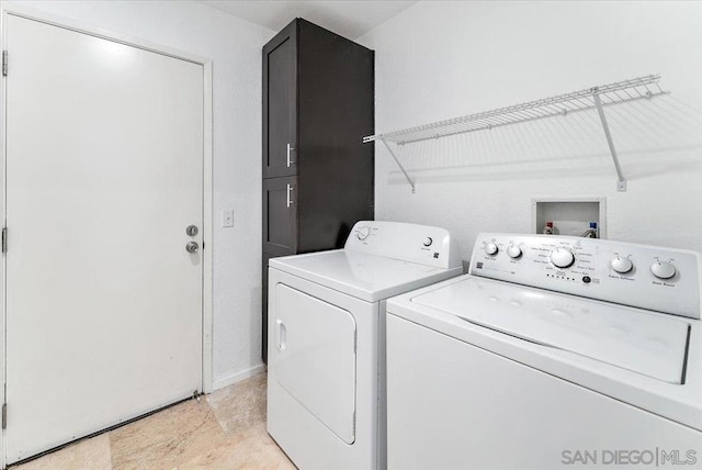 clothes washing area with washer and dryer and cabinets