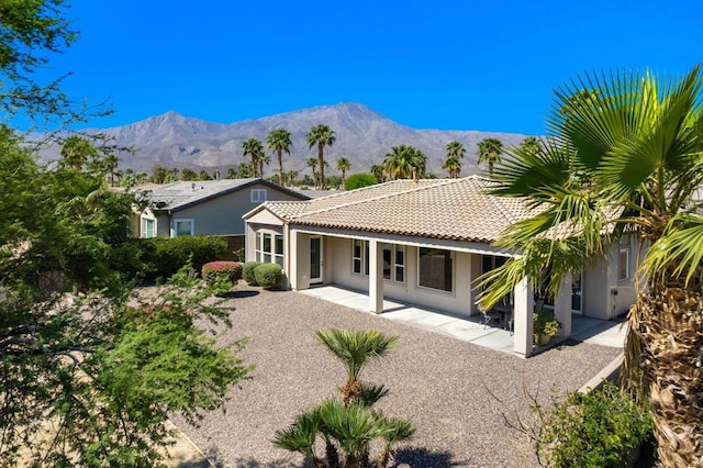 back of property with a mountain view and a patio area