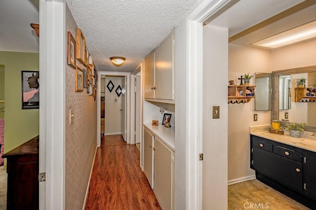 corridor with hardwood / wood-style floors and a textured ceiling