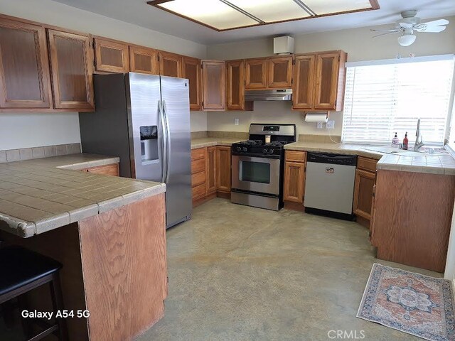 kitchen with stainless steel appliances, sink, tile countertops, and kitchen peninsula