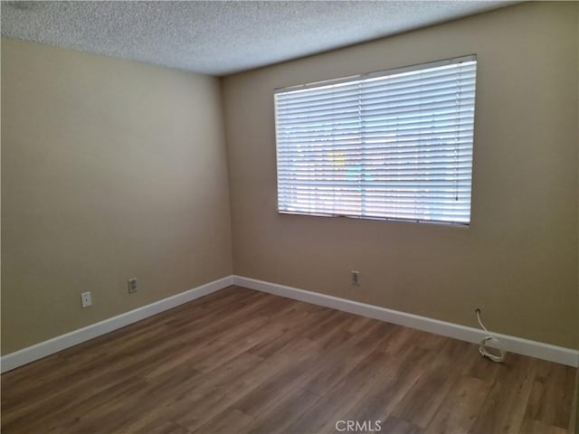 empty room with dark hardwood / wood-style floors and a textured ceiling